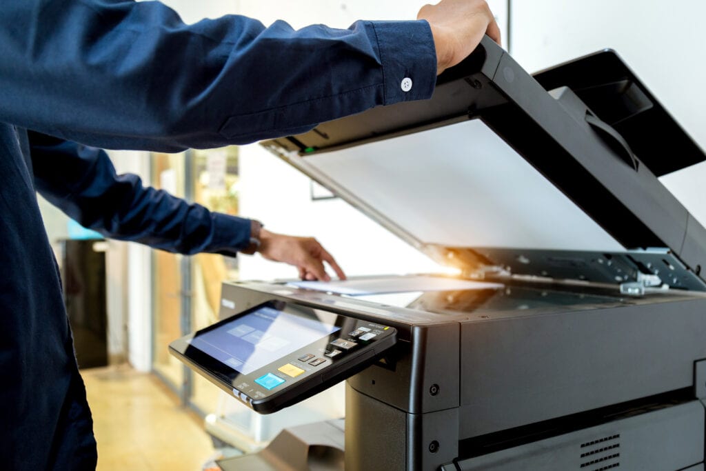 man scanning paper document on a copier