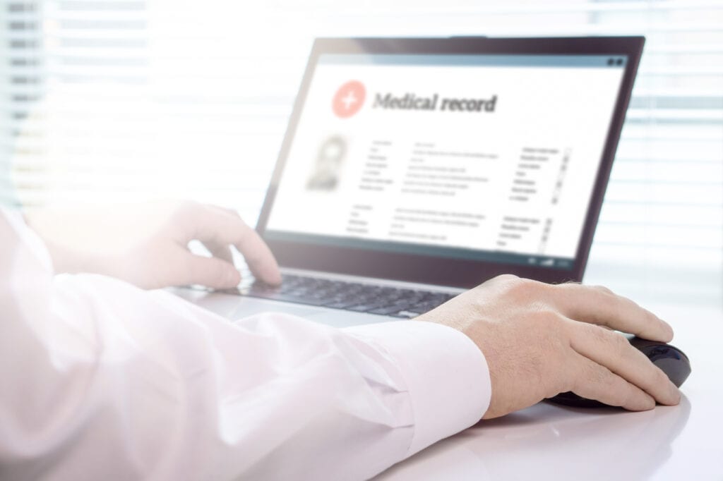 doctor using laptop with electronic medical records on screen